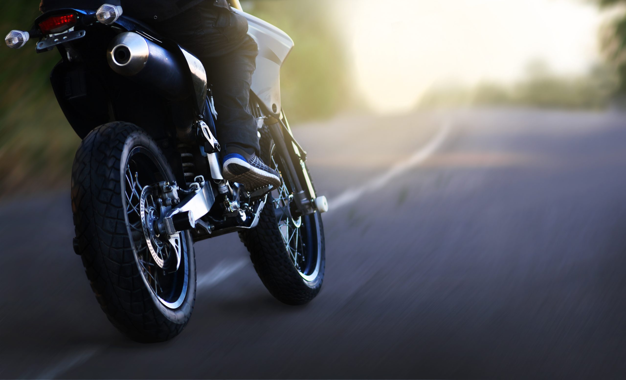 A motorcyclist rides at speed on the highway at sunrise